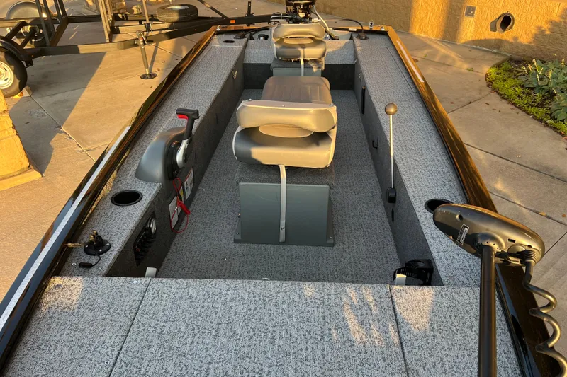 Slide: The Image of 2020 Tracker Panfish 16 boat interior with seating and controls, parked on concrete. - 4