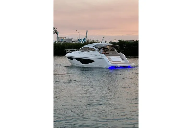Slide: The Image of 2024 Sessa Marine C44 Cruiser on water, with luxury waterfront homes and palm trees in the background. - 2