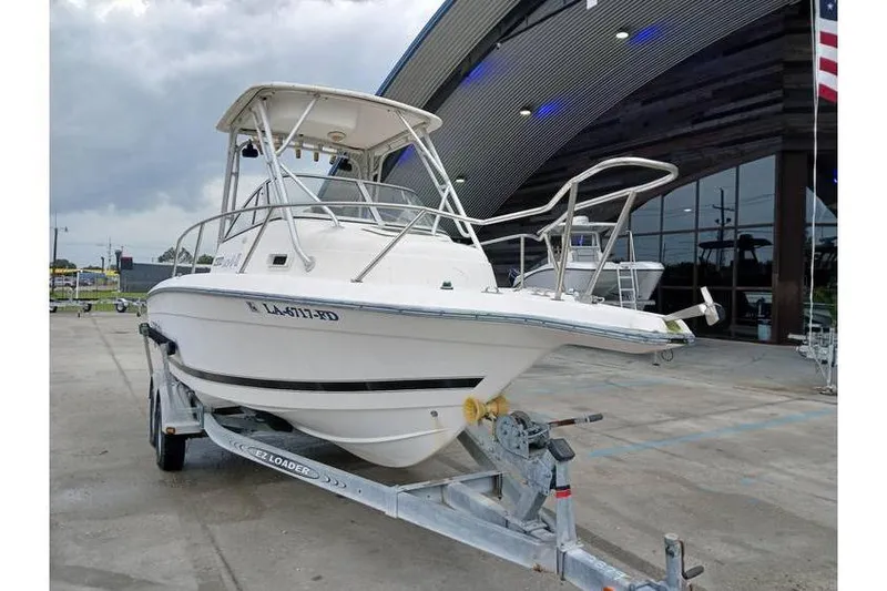 Slide: The Image of 1999 Century 2300 Walk-Around boat on trailer, parked outside a modern building. - 1