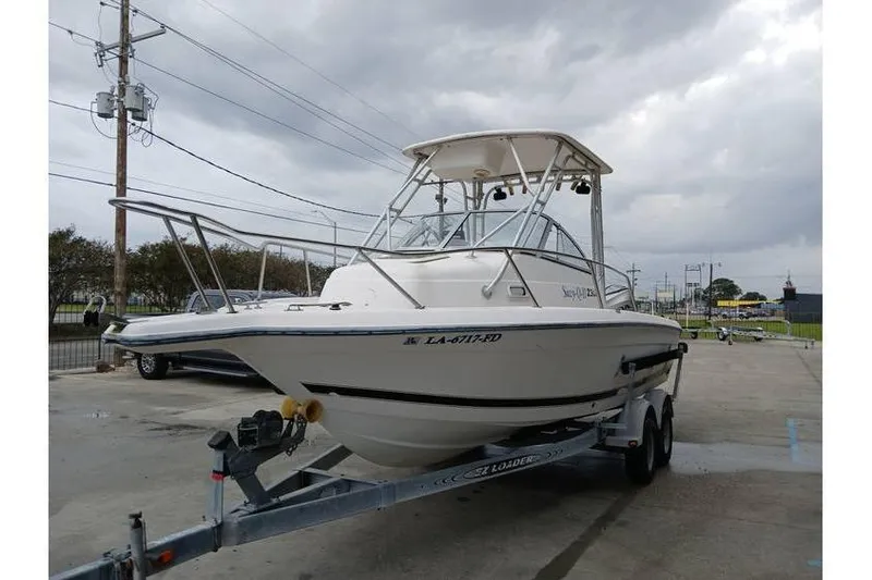 Slide: The Image of 1999 Century 2300 Walk-Around boat on trailer, parked outdoors under cloudy sky. - 2