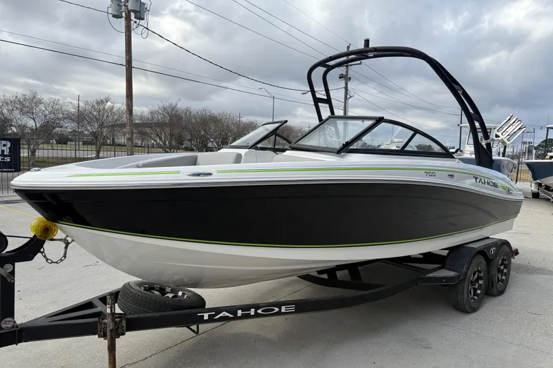 Slide: The Image of 2019 Tahoe 700 boat on trailer, black and white design, parked outdoors under cloudy sky. - 4