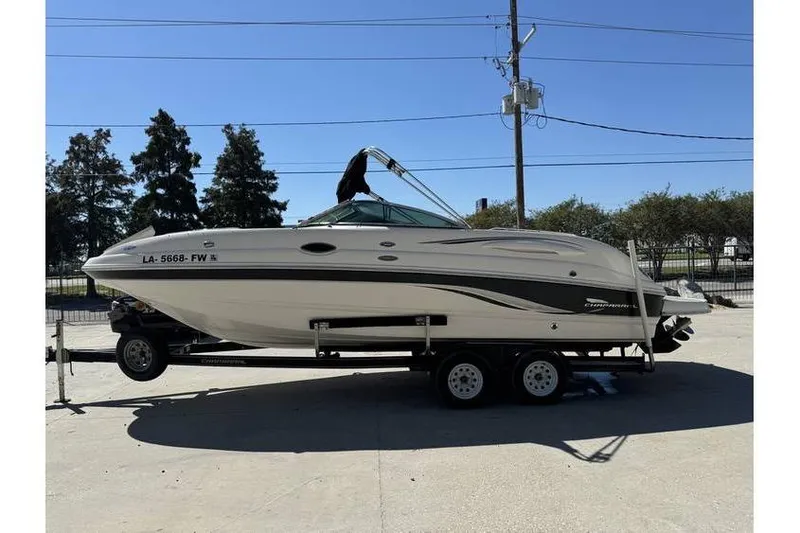 Slide: The Image of 2004 Chaparral Sunesta 254 boat on trailer, parked outdoors under clear sky. - 4