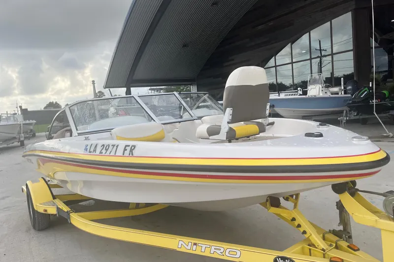 Slide: The Image of 2006 Nitro 189 Sport boat on trailer, parked outdoors near a modern building. - 1