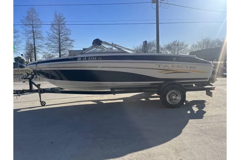 Slide: The Image of 2006 Tahoe 206 boat on trailer, parked outdoors under clear sky. - 4