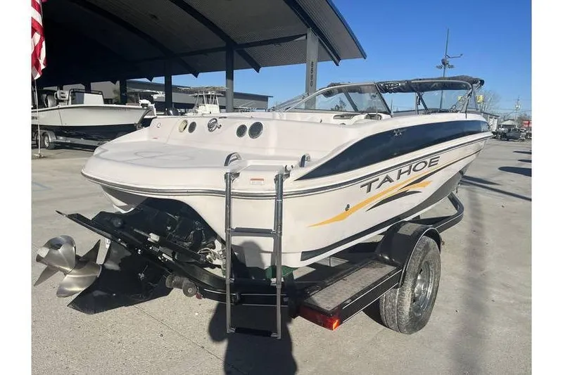 Slide: The Image of 2006 Tahoe 206 boat on trailer, parked outdoors under a canopy. - 7