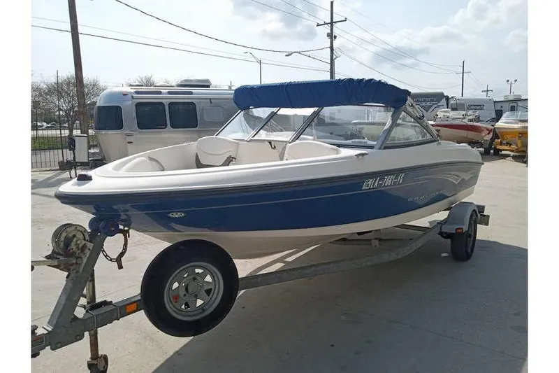 Slide: The Image of 2008 Bayliner 175 boat on trailer with blue canopy in outdoor setting. - 2