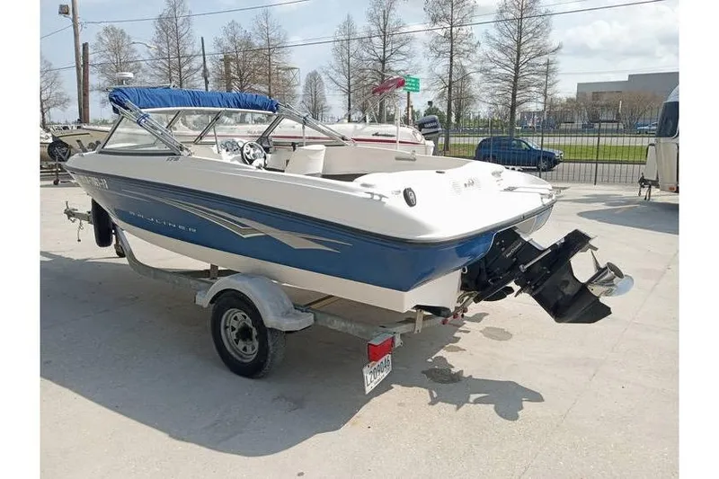 Slide: The Image of 2008 Bayliner 175 boat on trailer, blue and white, parked outdoors. - 3