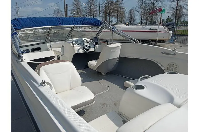Slide: The Image of 2008 Bayliner 175 boat interior with white seating and blue canopy, parked outdoors. - 7