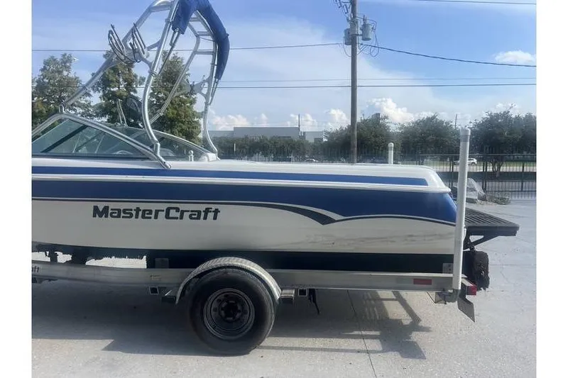 Slide: The Image of 1999 MasterCraft Prostar 205 boat on trailer, blue and white design, parked outdoors. - 2
