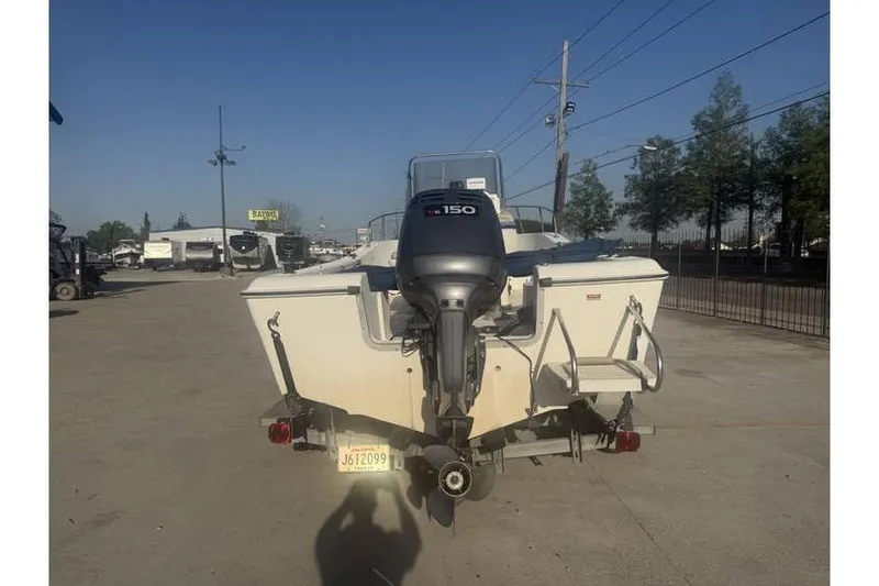Slide: The Image of 1999 Cobia 194 Center Console boat with outboard motor, parked outdoors. - 4