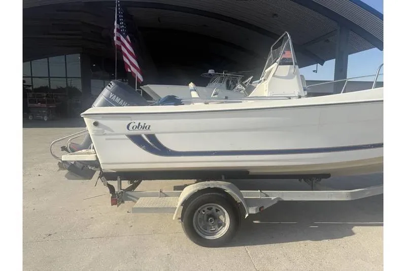 Slide: The Image of 1999 Cobia 194 Center Console boat on trailer, American flag, Yamaha motor visible. - 5