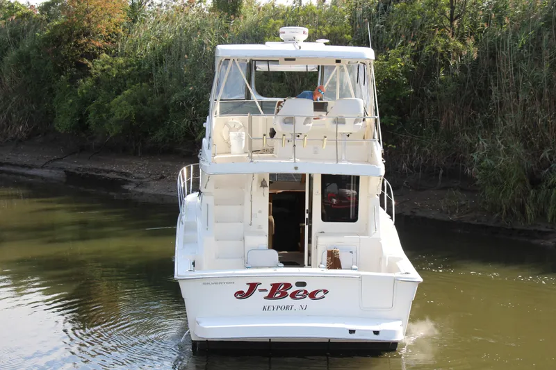 Slide: The Image of 2003 Silverton 38 Convertible boat navigating a narrow waterway, surrounded by lush greenery. - 13