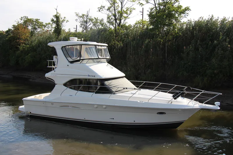 Slide: The Image of 2003 Silverton 38 Convertible yacht on calm water, surrounded by lush greenery. - 14