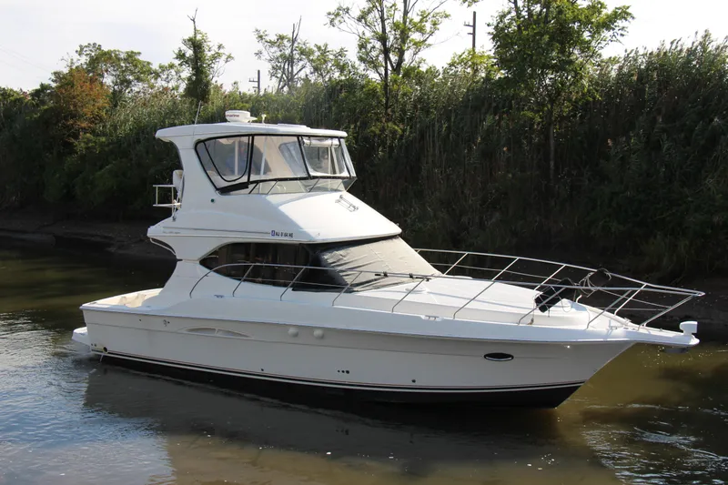 Slide: The Image of 2003 Silverton 38 Convertible yacht on calm water, surrounded by lush greenery. - 15
