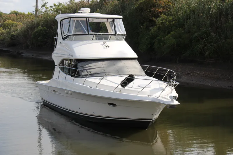 Slide: The Image of 2003 Silverton 38 Convertible yacht cruising on a calm river, surrounded by lush greenery. - 17