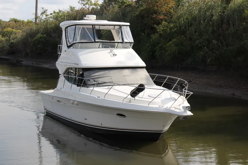 Slide: The Image of 2003 Silverton 38 Convertible yacht cruising on a calm river, surrounded by lush greenery. - 18