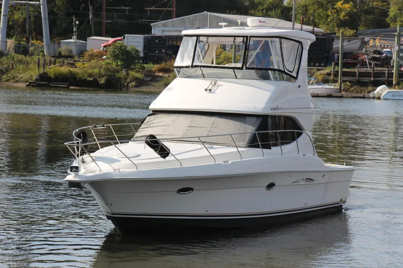 Slide: The Image of 2003 Silverton 38 Convertible yacht on calm water near a marina. - 2