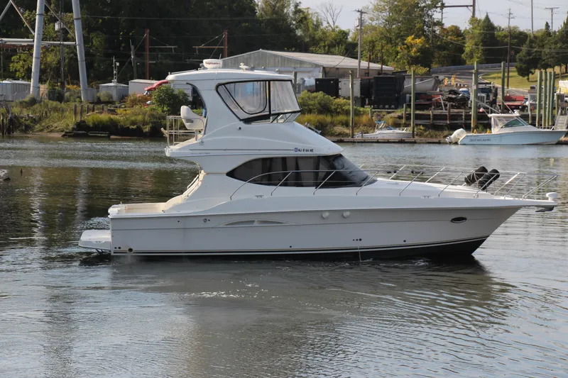 Slide: The Image of 2003 Silverton 38 Convertible yacht on calm water near a marina. - 21