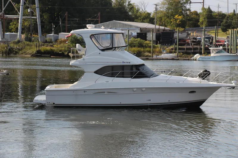 Slide: The Image of 2003 Silverton 38 Convertible yacht on calm water near a marina. - 23
