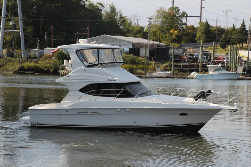 Slide: The Image of 2003 Silverton 38 Convertible yacht cruising on a calm river near a marina. - 24