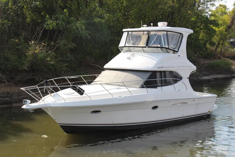 Slide: The Image of 2003 Silverton 38 Convertible yacht on calm water, surrounded by lush greenery. - 3