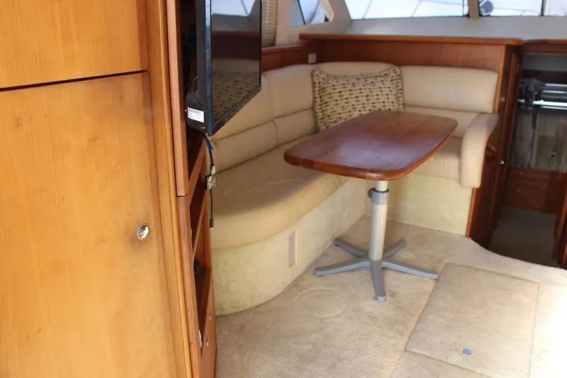 Slide: The Image of Interior of 2003 Silverton 38 Convertible yacht with beige seating and wooden table. - 35