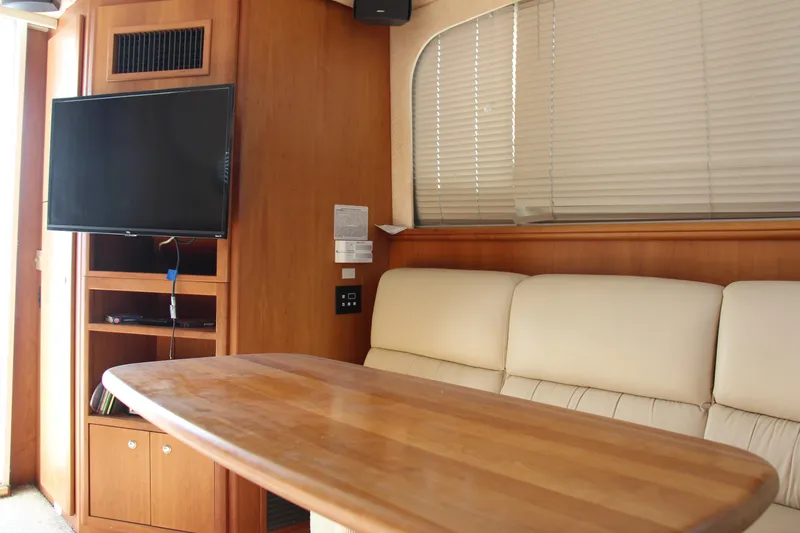 Slide: The Image of Interior of 2003 Silverton 38 Convertible yacht with TV, wooden table, and cream sofa. - 36