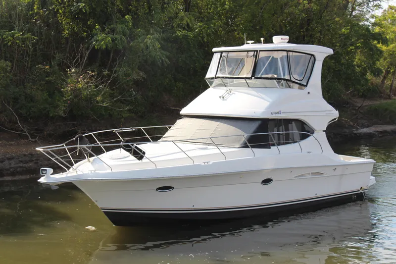 Slide: The Image of 2003 Silverton 38 Convertible yacht on calm water, surrounded by lush greenery. - 4