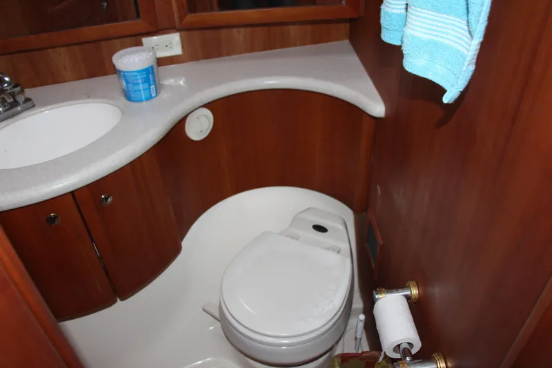 Slide: The Image of 2003 Silverton 38 Convertible yacht bathroom with toilet, sink, and wooden cabinetry. - 49