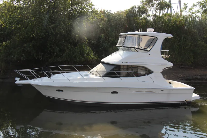 Slide: The Image of 2003 Silverton 38 Convertible yacht on calm water, surrounded by lush greenery. - 6