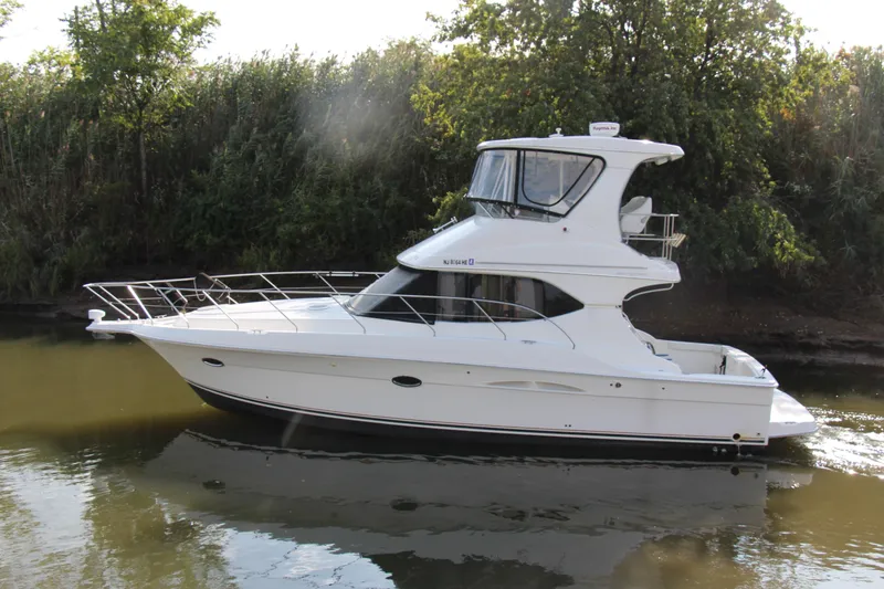 Slide: The Image of 2003 Silverton 38 Convertible yacht cruising on a calm river, surrounded by lush greenery. - 7