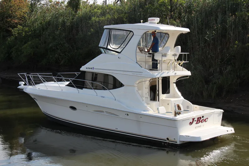 Slide: The Image of 2003 Silverton 38 Convertible yacht cruising on a calm river, surrounded by lush greenery. - 9
