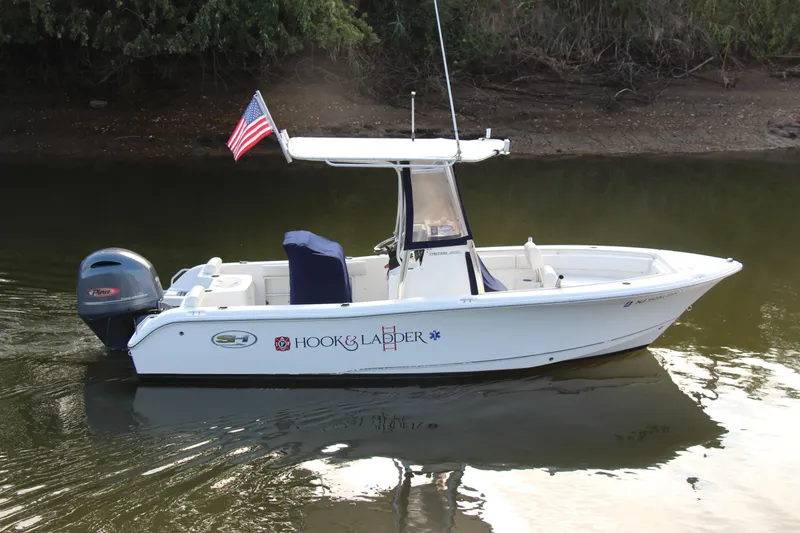 Slide: The Image of 2019 Sea Hunt Triton 210 boat with American flag on calm water. - 1