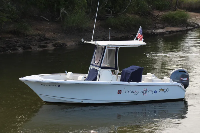 Slide: The Image of 2019 Sea Hunt Triton 210 boat on calm water, featuring an American flag. - 10