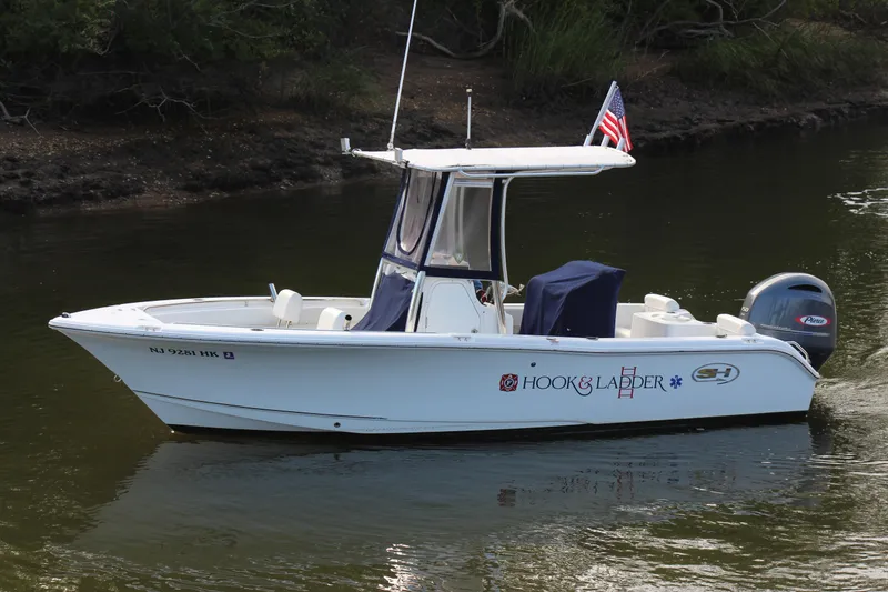 Slide: The Image of 2019 Sea Hunt Triton 210 boat on calm water, featuring "Hook & Ladder" branding. - 11