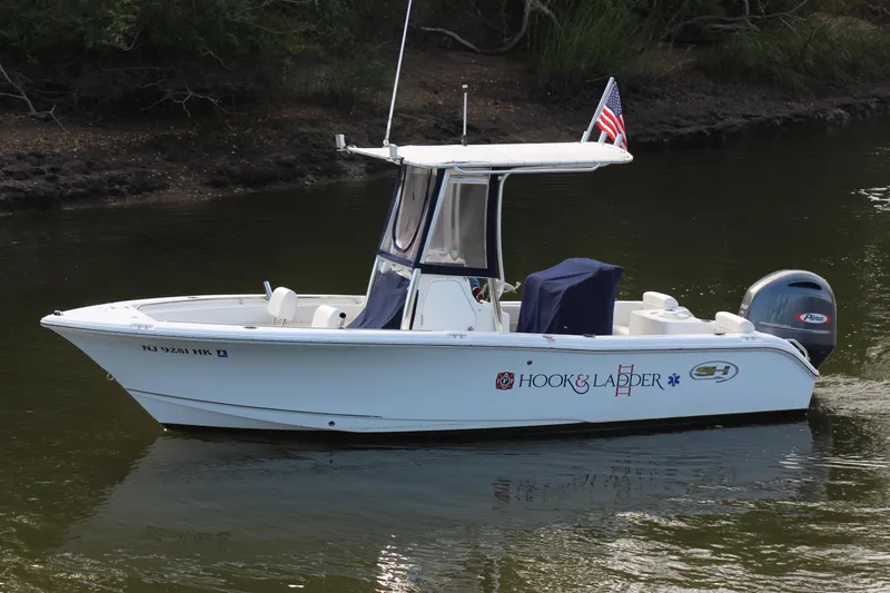 Slide: The Image of 2019 Sea Hunt Triton 210 boat on water, American flag, side view. - 12