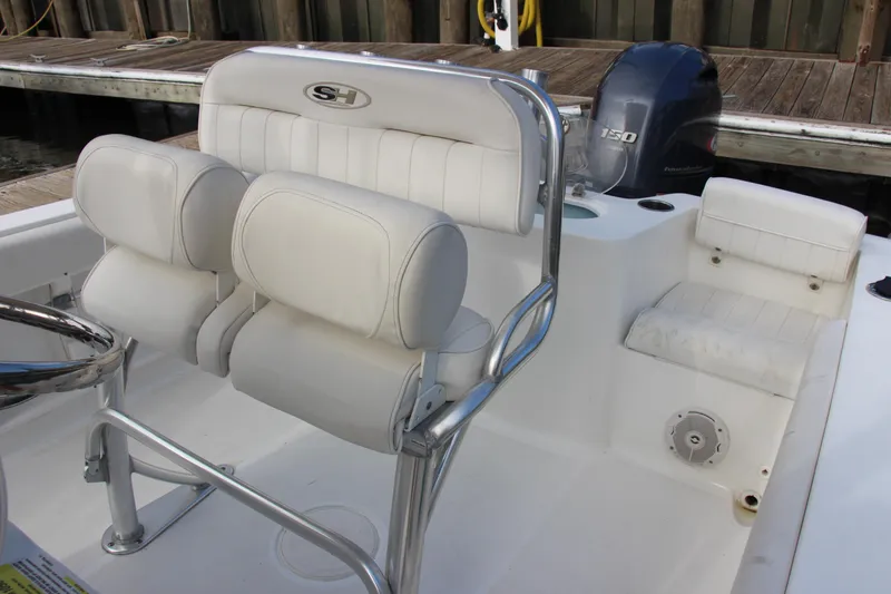 Slide: The Image of 2019 Sea Hunt Triton 210 boat interior with white seating and steering wheel. - 16