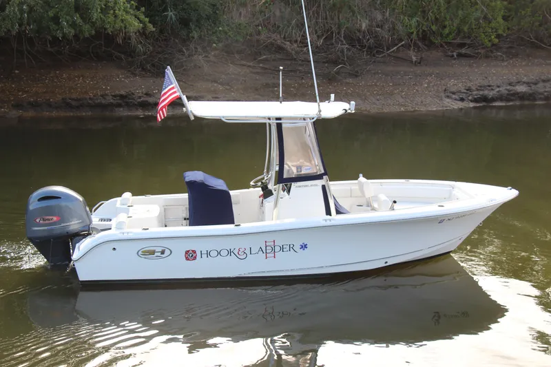 Slide: The Image of 2019 Sea Hunt Triton 210 boat with American flag on calm water. - 2