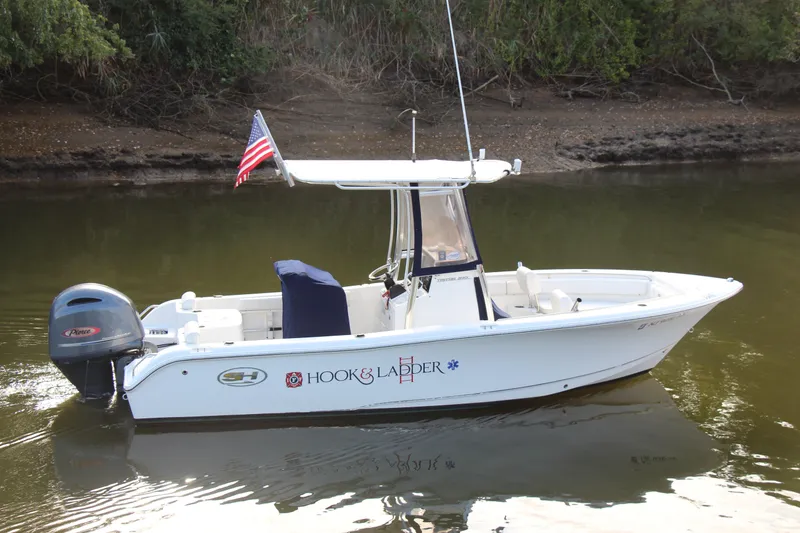 Slide: The Image of 2019 Sea Hunt Triton 210 boat with American flag on calm water. - 3