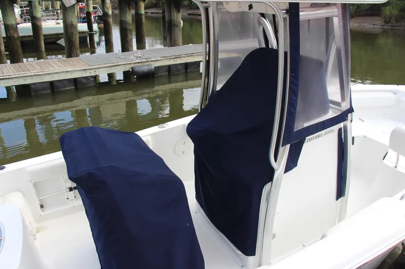 Slide: The Image of 2019 Sea Hunt Triton 210 boat with covered seats, docked by a wooden pier. - 37