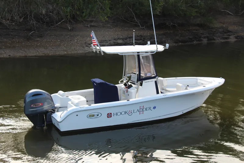 Slide: The Image of 2019 Sea Hunt Triton 210 boat on calm water, featuring a sleek design and outboard motor. - 4