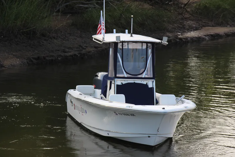 Slide: The Image of 2019 Sea Hunt Triton 210 boat on calm water with American flag. - 6
