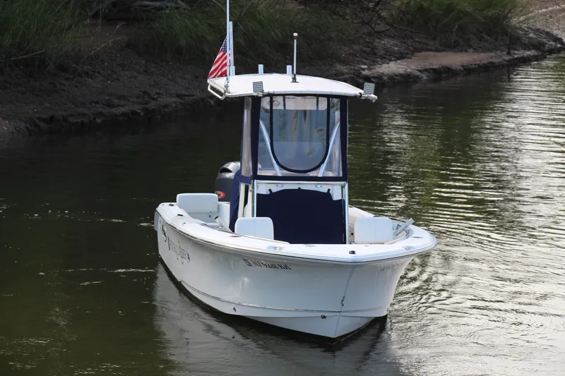 Slide: The Image of 2019 Sea Hunt Triton 210 boat on calm water with American flag. - 7