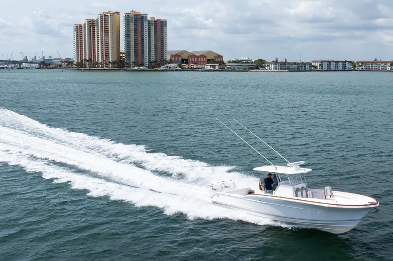 Slide: The Image of 2026 Buddy Davis 34 Center Console boat cruising on water near coastal buildings. - 25