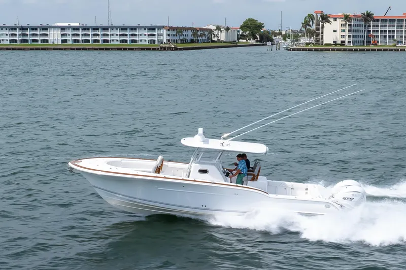 Slide: The Image of 2026 Buddy Davis 34 Center Console boat cruising on water near coastal buildings. - 45