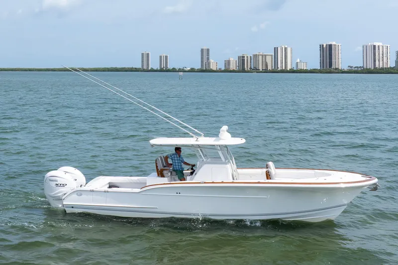 Slide: The Image of 2026 Buddy Davis 34 Center Console boat cruising on water with city skyline backdrop. - 49
