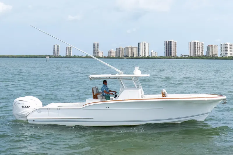 Slide: The Image of 2026 Buddy Davis 34 Center Console boat cruising on water with city skyline backdrop. - 52
