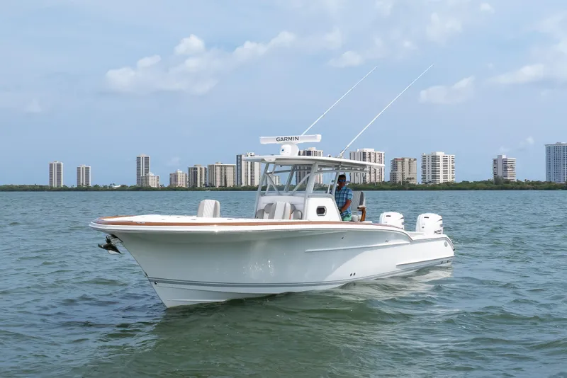 Slide: The Image of 2026 Buddy Davis 34 Center Console boat cruising on water with city skyline backdrop. - 6