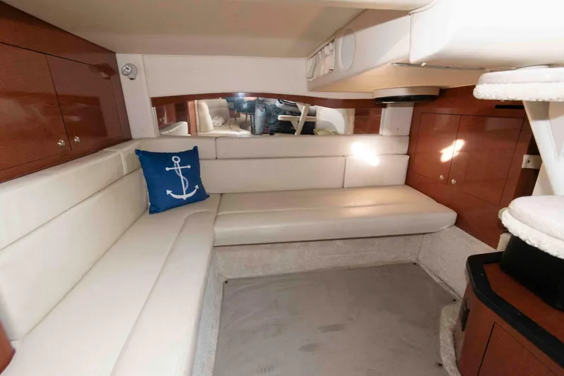 Slide: The Image of Interior of 2004 Sea Ray 340 Sundancer with white seating and anchor-themed pillow. - 16