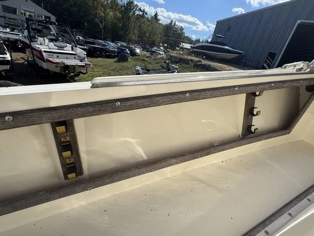 Slide: The Image of 1990 Mako 201 boat interior with wooden trim and rod holders, parked outdoors. - 15